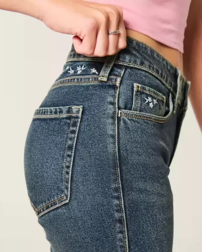 Hoch geschnittene Schlagjeans mit dunkler Waschung und Blumenstickerei Hoch geschnittene Schlagjeans mit dunkler Waschung und Blumenstickerei
