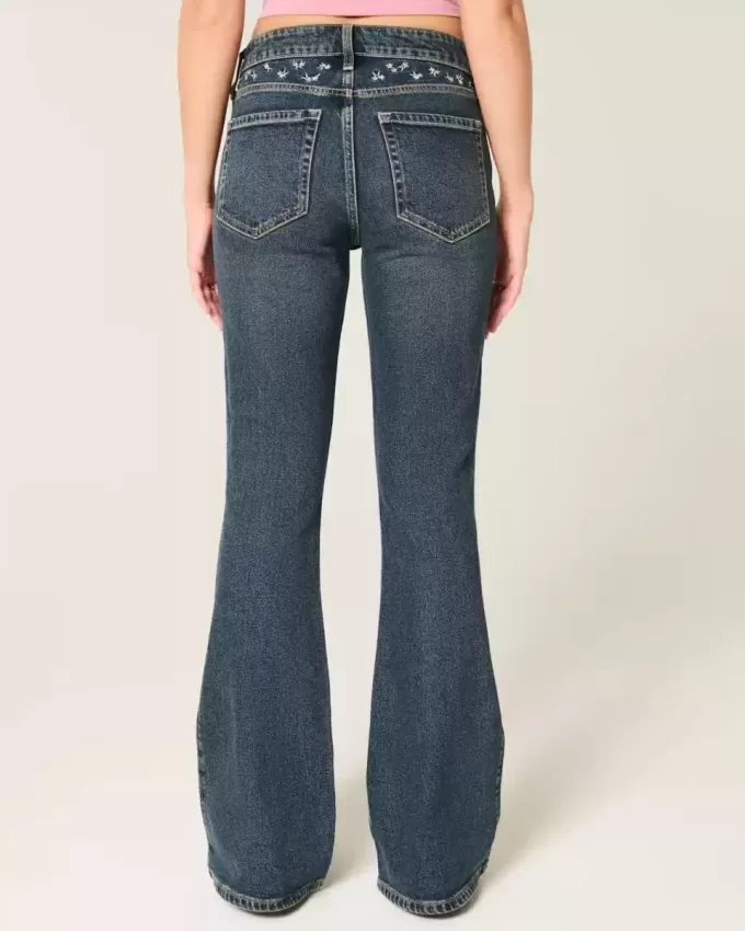 Hoch geschnittene Schlagjeans mit dunkler Waschung und Blumenstickerei Hoch geschnittene Schlagjeans mit dunkler Waschung und Blumenstickerei