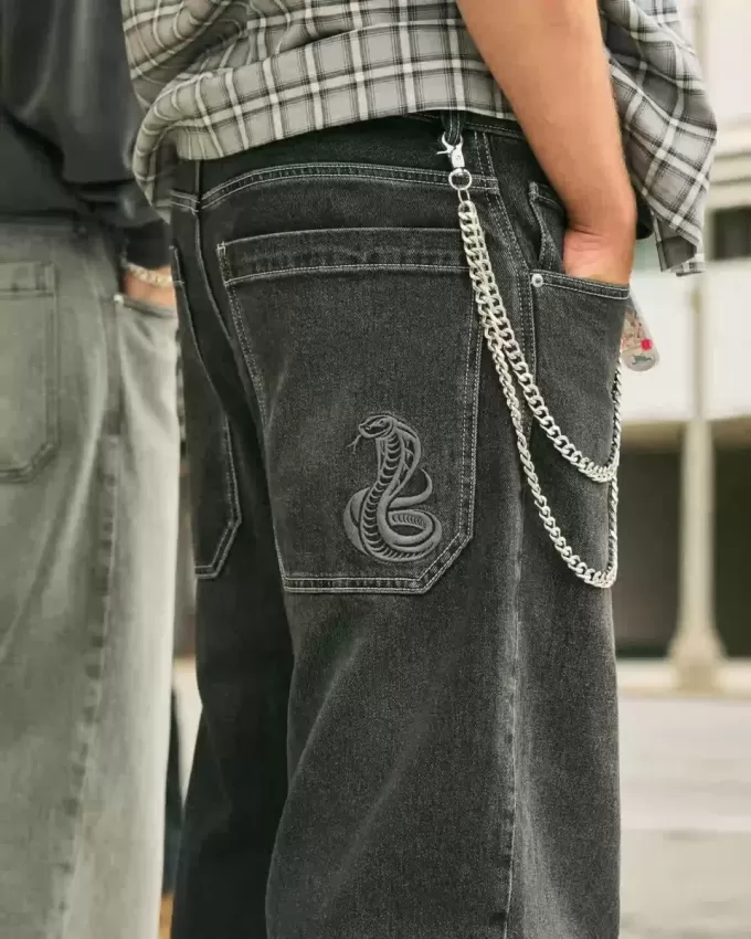 Verwaschene schwarze Skater-Baggy-Jeans mit Schlangenstickerei Verwaschene schwarze Skater-Baggy-Jeans mit Schlangenstickerei